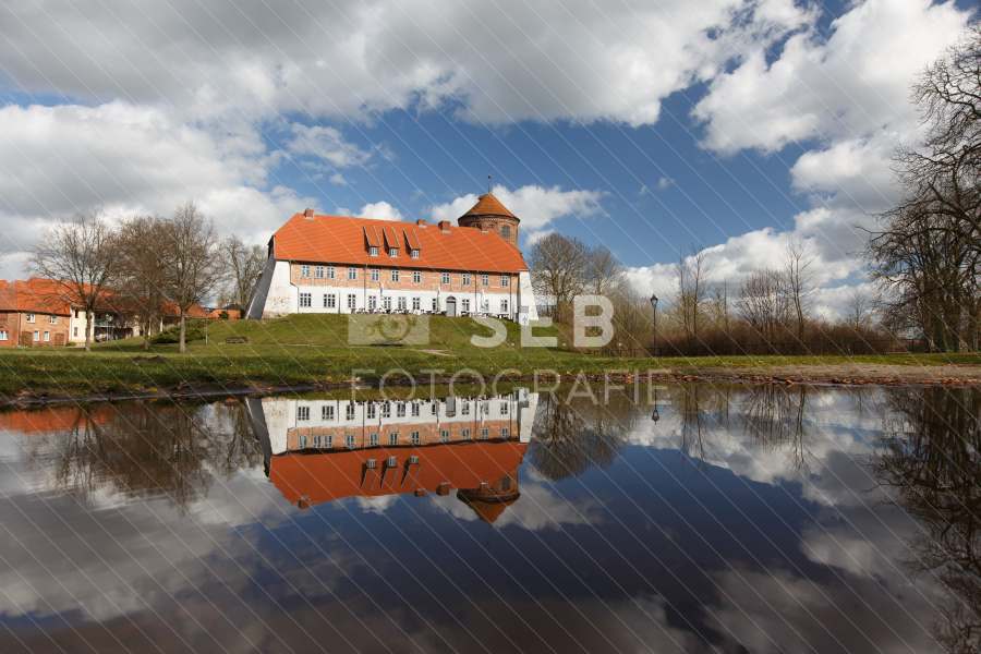 Die Neustädter Burg spiegelt sich in einer Pfütze im Herbst